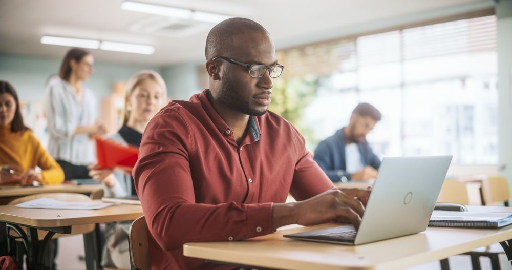 Adult Education Center: Black Student Learning in Classroom, Using Laptop to Write Down Notes.