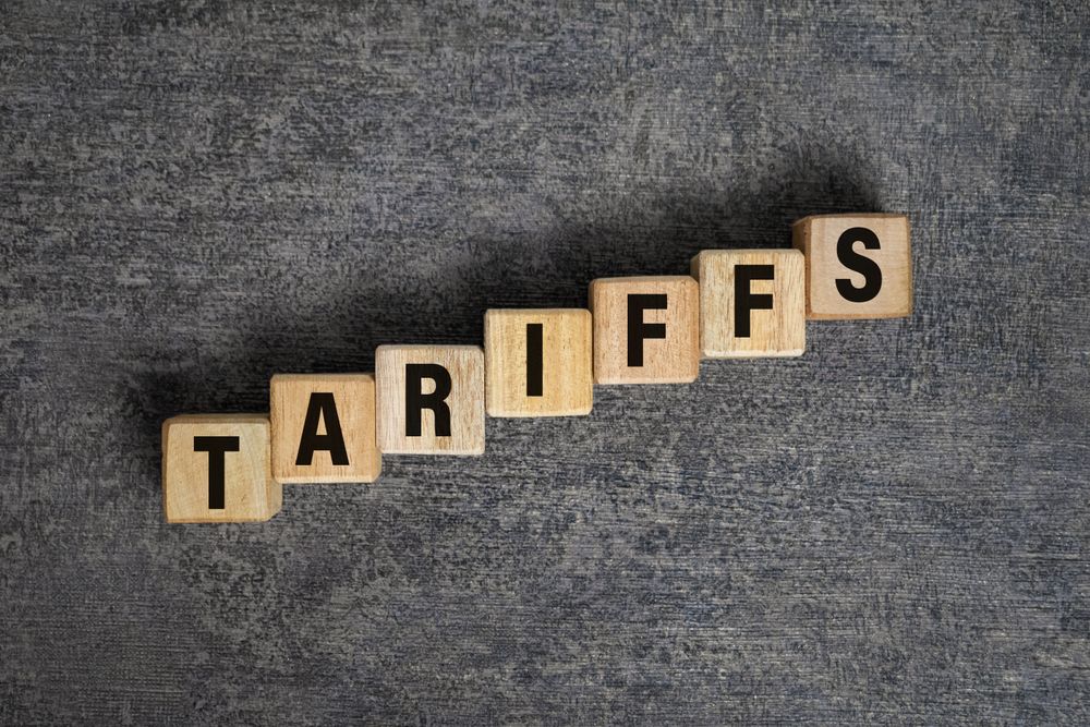 tariffs word text on raising wooden blocks isolated on dark cement background