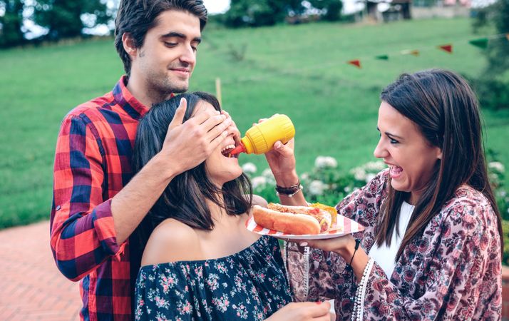 Man holding friend's eyes closed as friends do a funny taste test