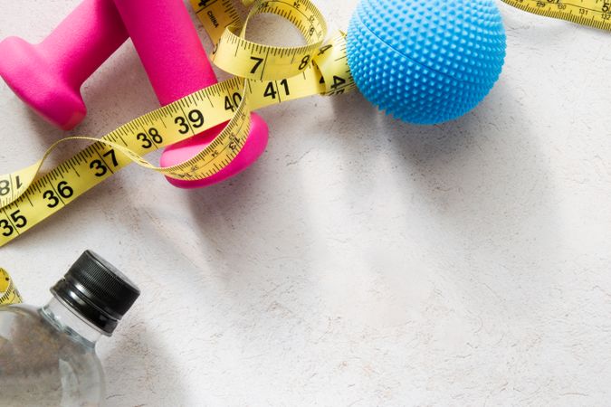 Workout Theme: Dumbbells, Water Bottle, Massage Ball, And Measuring Tape on Fitness-Inspired Background