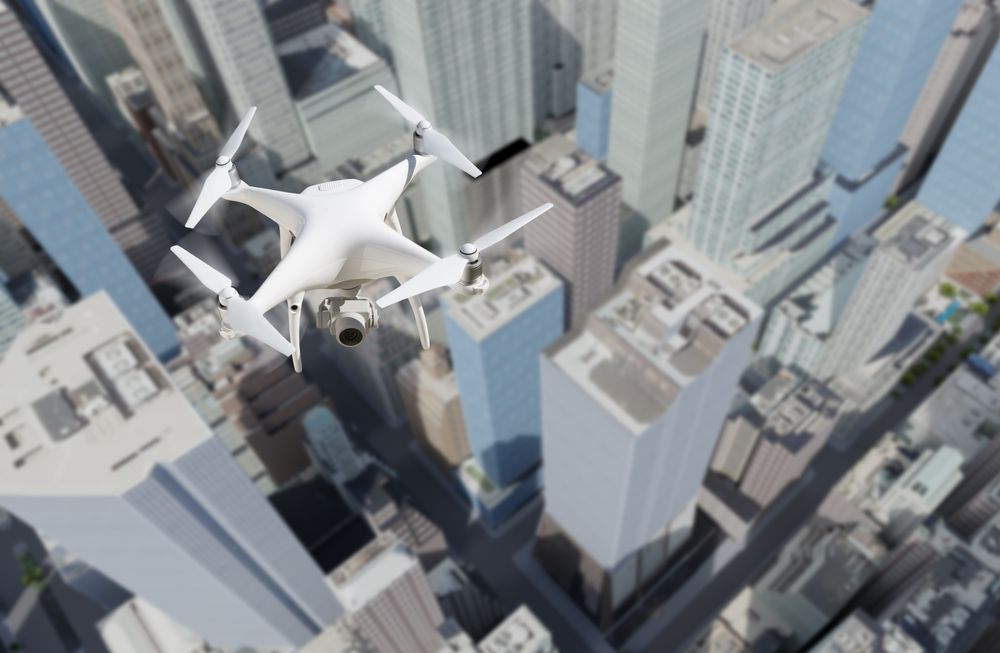 Unmanned Aircraft System Quadcopter Drone In The Air Above City and Corporate Buildings.