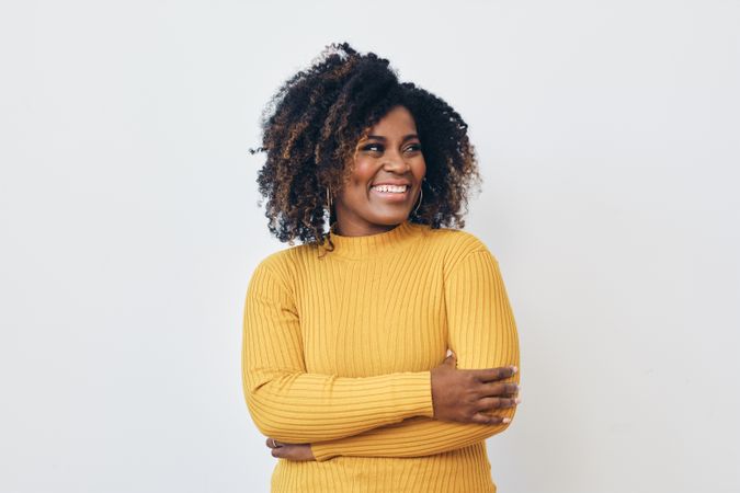 Studio shot of a confident Black woman in yellow shirt with her arms crossed