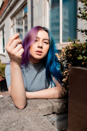 Woman with hair dyed blue and magenta beside a building