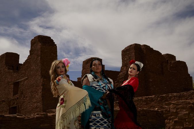 Native American woman and two Hispanic women standing beside an ancient site