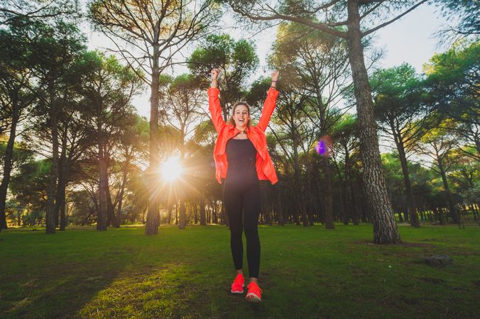 Excited sportswoman with arms raised in park