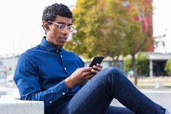 Attentive businessman chatting on smartphone in town