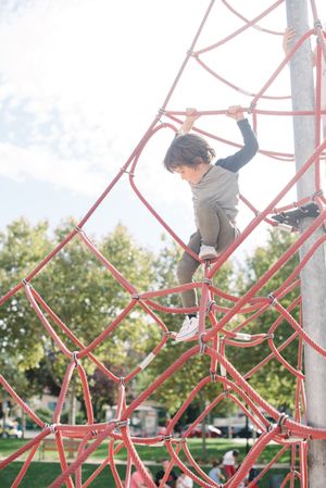 Boy on rope climbing net in sunlight