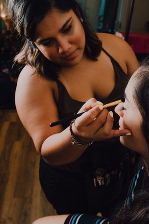 Young woman getting makeup by makeup artist in salon