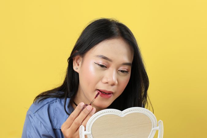 Asian Young Woman, Make Up Face by Applying Red Lipstick, Lips Balm on her Lips using Lip Applicator.
