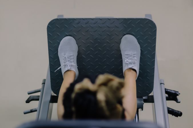 close up of a woman's head using a leg press machine in a fitness center environment.