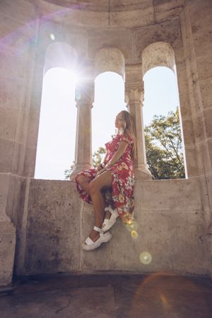 Woman sitting on columned marble fence