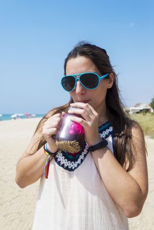 A young woman on the beach sipping a drink