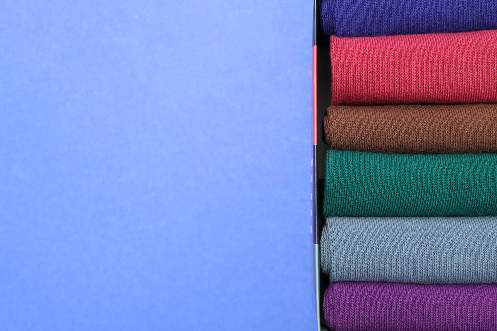 Box with socks on blue background, space for text