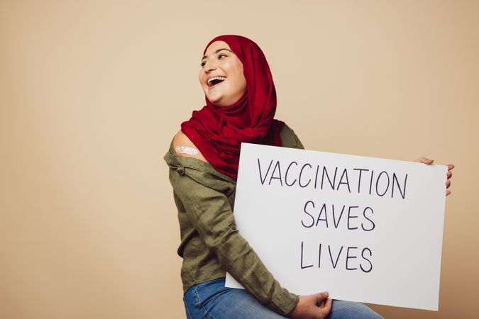 Cheerful woman holding a banner with "vaccination saves lives" slogan