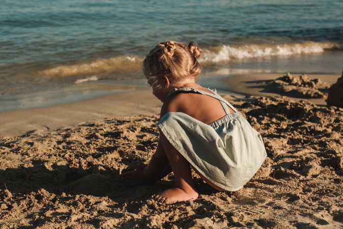 Little girl sitting on sandy beach