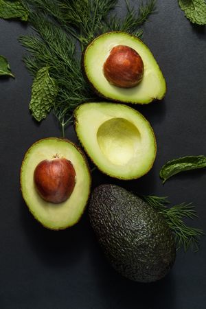 Close up of avocados cut into halves on a dark background