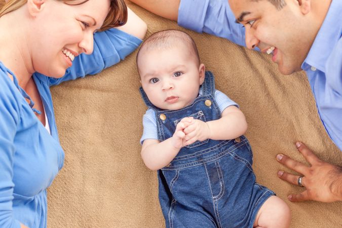 Young Couple Laying With Their Infant On A Blanket