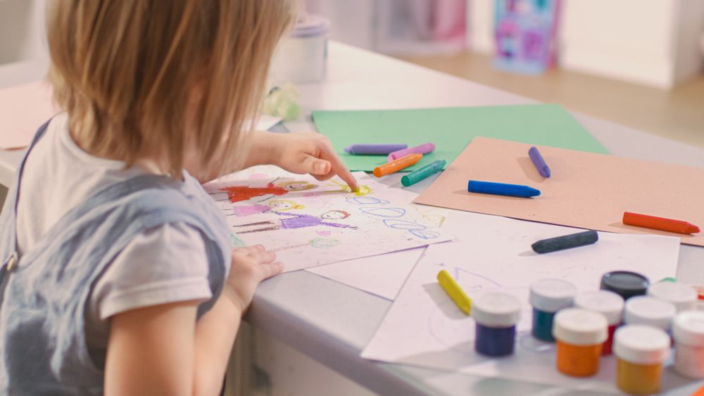 Back Shot of a Cute Little Girl Sits at Her Table and Draws.
