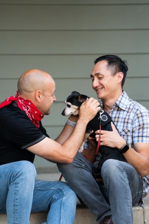 Male partners having fun giving affection to their rescue dog on their front porch