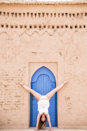 Woman in handstand against old stone wall