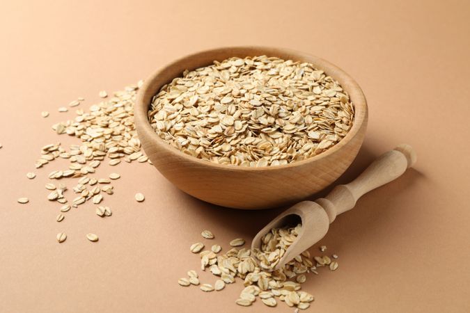 Bowl and scoop with oatmeal flakes on craft background