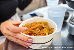 Woman holding plastic cup of pasta bE8OV4
