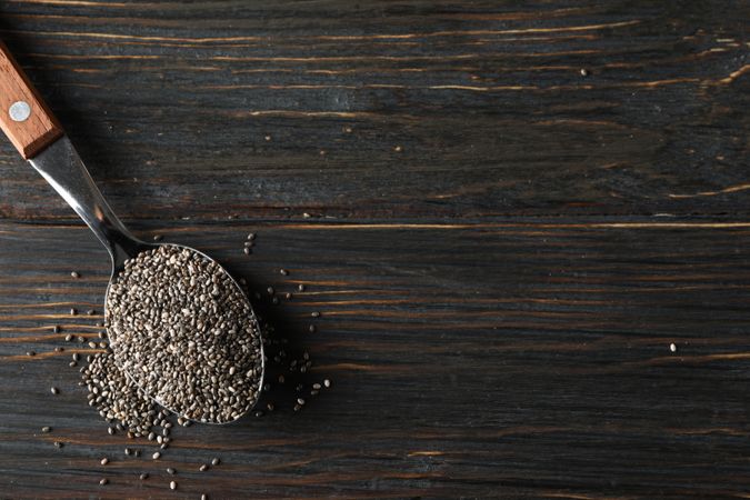 Spoon with chia on wooden background, copy space
