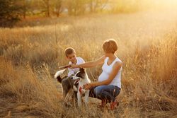 Female and male child grooming husky in nature