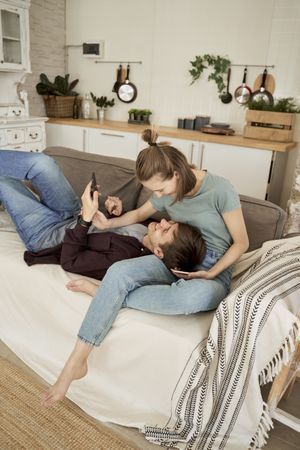 Chilling couple spending time together on sofa browsing smartphone