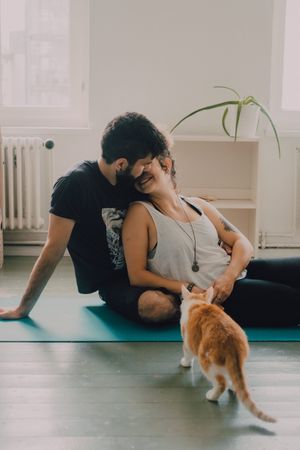 Loving couple cuddling on floor while cat walking around