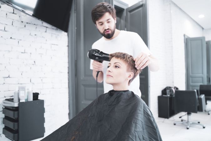 Hairdresser drying hair to woman