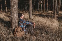 Relaxed tourist resting by tree in forest