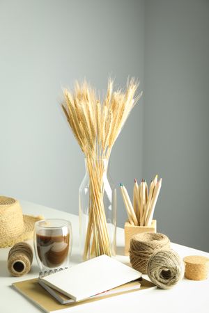 Work table with yarn, notebooks, pencils, dried flowers, with hat and copy space