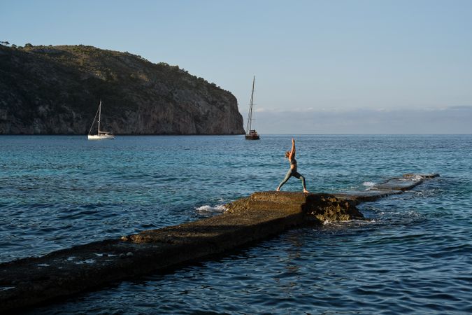 Fit woman exercising on rocky pier