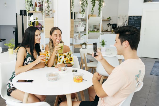 Man taking picture of friends in cafe