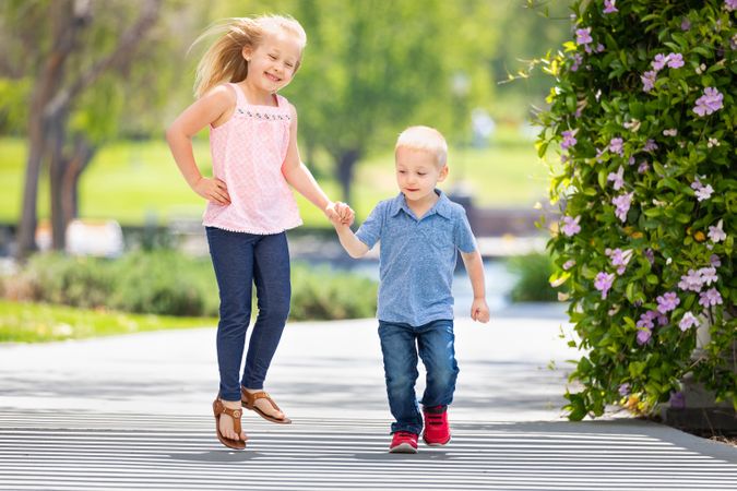 Young Sister and Brother Holding Hands And Running At The Park