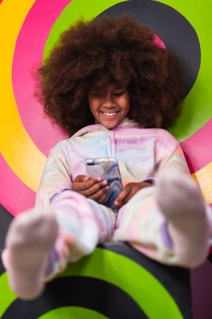Smiling Black girl using mobile phone in studio