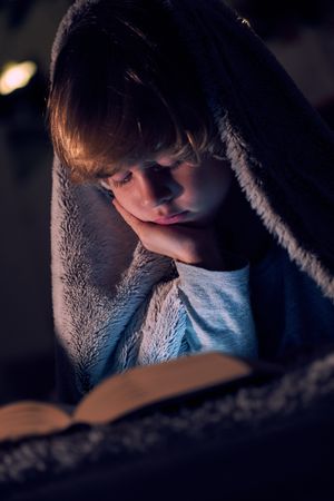 Boy reading book in darkness