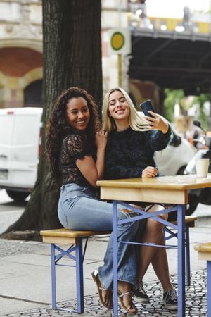 Friends taking selfie in street cafe