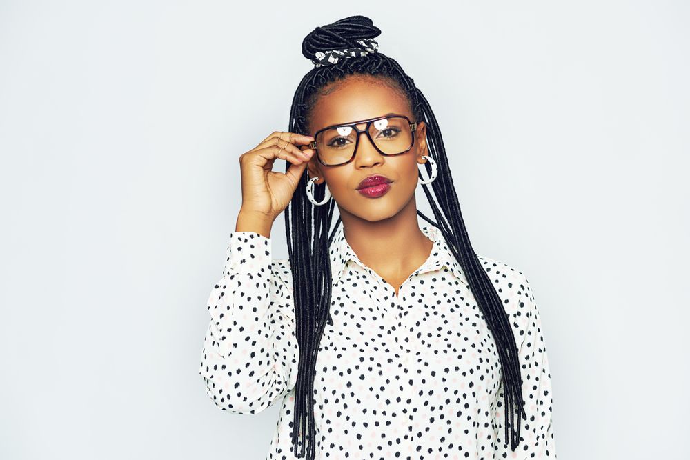 Studio portrait of confident woman with a serious expression adjusting her glasses