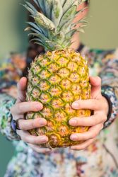 Woman holding pineapple between her hands