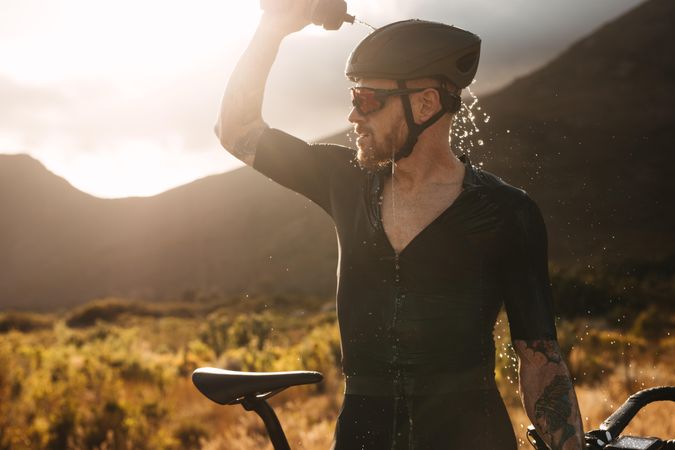 Tired bicycle racer cooling himself with water during break from training