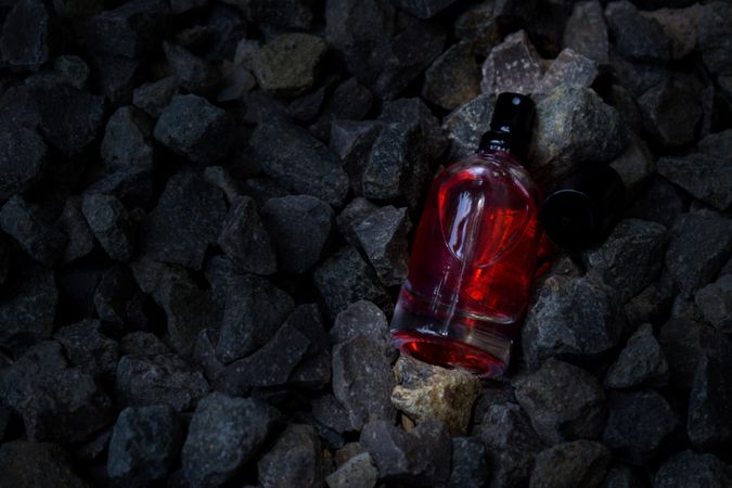 Red perfume bottle mock up laying in the rocks
