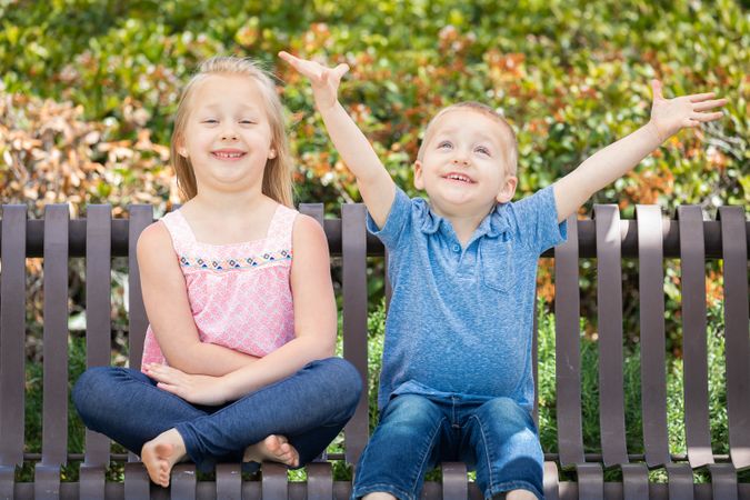Young Sister and Brother Having Fun On The Bench At The Park