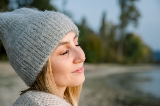 A young woman breathes clean air, looks at the sky with a smile and closed eyes