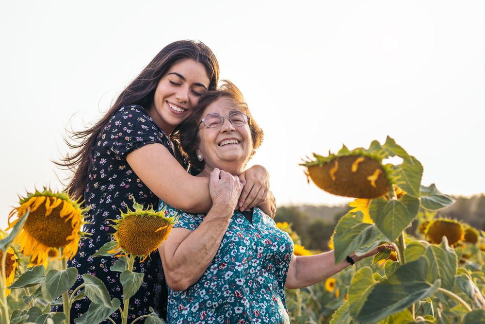 Taking advantage of life Grandmother and granddaughter in a field of sunflowers.