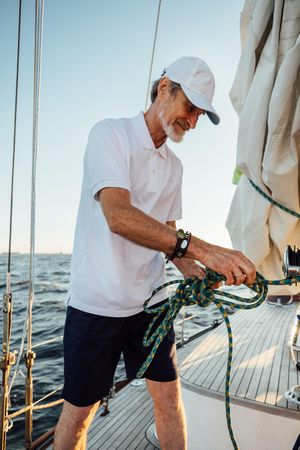 Older man making a knot on a sailboat