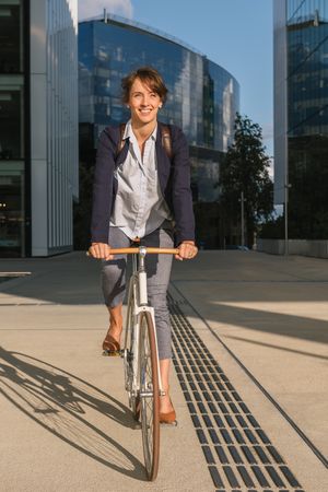 Cheerful businesswoman riding bicycle on street