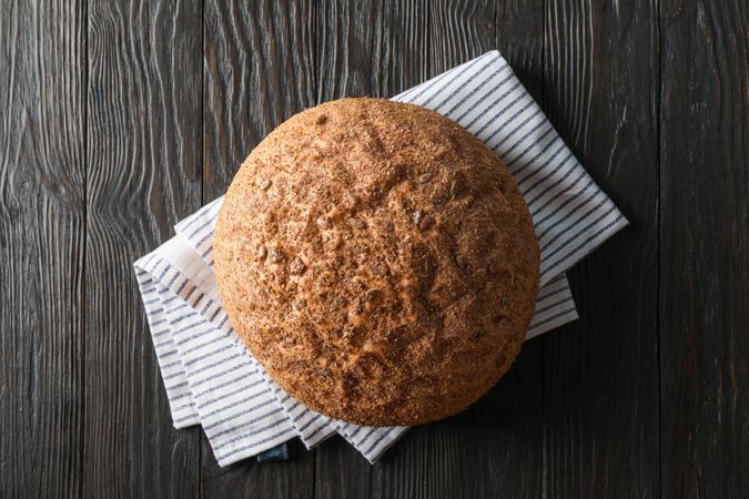 Bread on kitchen towel on wooden background, space for text and top view
