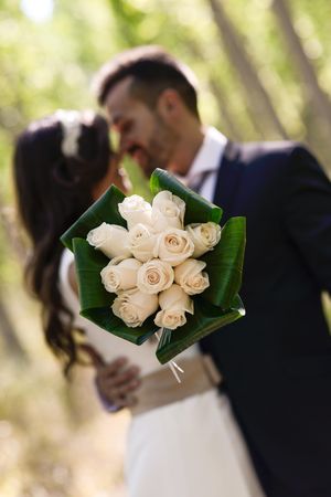 Bouquet of roses with newlyweds in the background